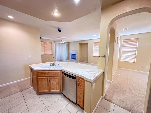 kitchen featuring a sink, tile counters, light carpet, dishwasher, and open floor plan