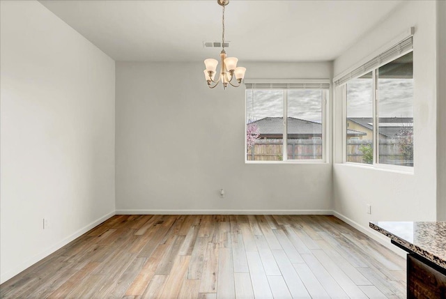 unfurnished dining area with a chandelier, visible vents, light wood-style flooring, and baseboards