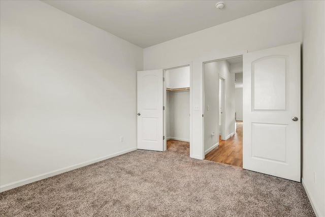 unfurnished bedroom featuring a walk in closet, carpet, baseboards, and a closet