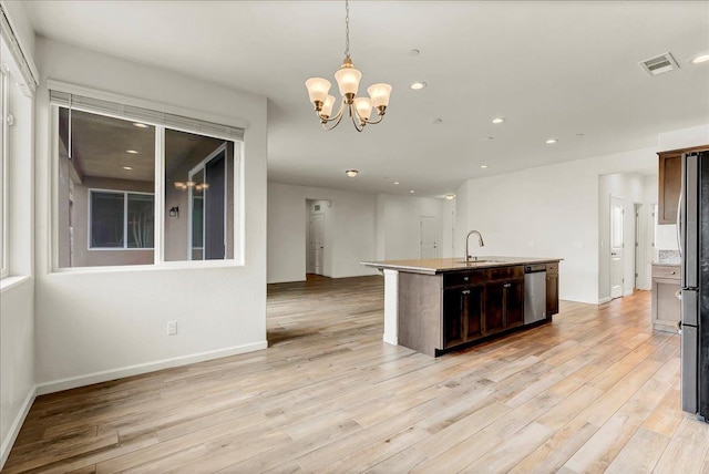 kitchen with light wood finished floors, visible vents, an island with sink, stainless steel dishwasher, and a sink