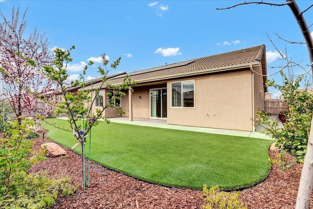 back of property featuring stucco siding, a fenced backyard, a yard, solar panels, and a patio area