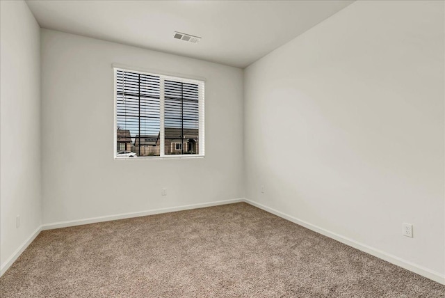 carpeted spare room featuring baseboards and visible vents