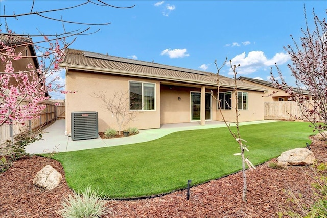 rear view of house with stucco siding, a patio, central AC unit, and a fenced backyard