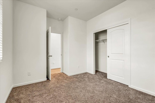 unfurnished bedroom with a closet, baseboards, and carpet flooring