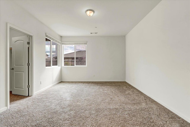 carpeted spare room featuring baseboards and visible vents