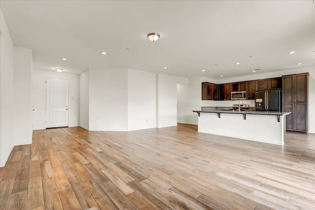 unfurnished living room featuring light wood-style flooring, recessed lighting, and a sink