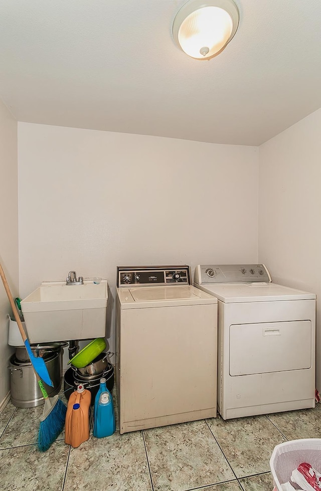 laundry area featuring light tile patterned floors, laundry area, washer and dryer, and a sink