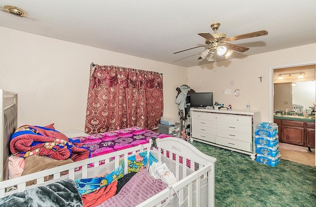 carpeted bedroom featuring ensuite bathroom and a ceiling fan