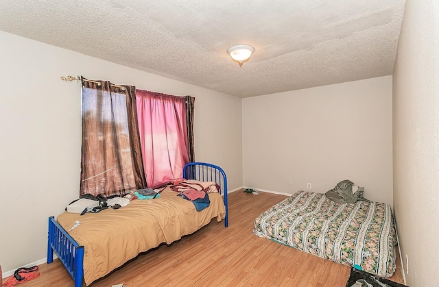 bedroom featuring wood finished floors, baseboards, and a textured ceiling