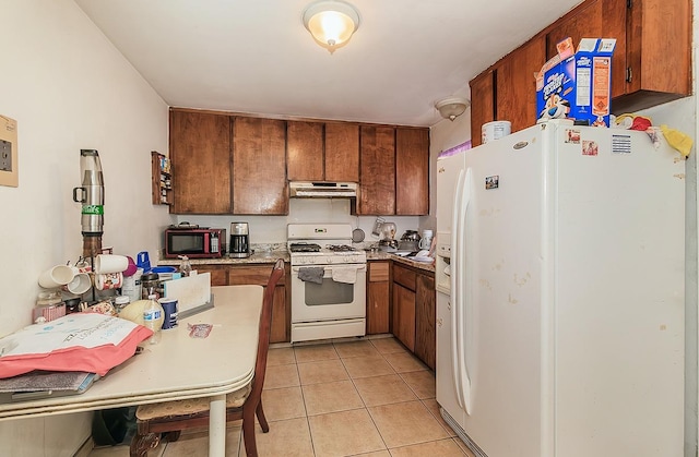 kitchen featuring under cabinet range hood, light tile patterned floors, white appliances, and brown cabinetry