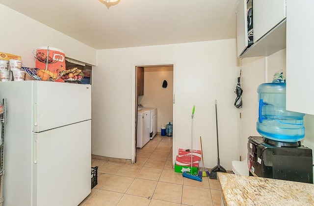 kitchen featuring light tile patterned floors, separate washer and dryer, light countertops, and freestanding refrigerator