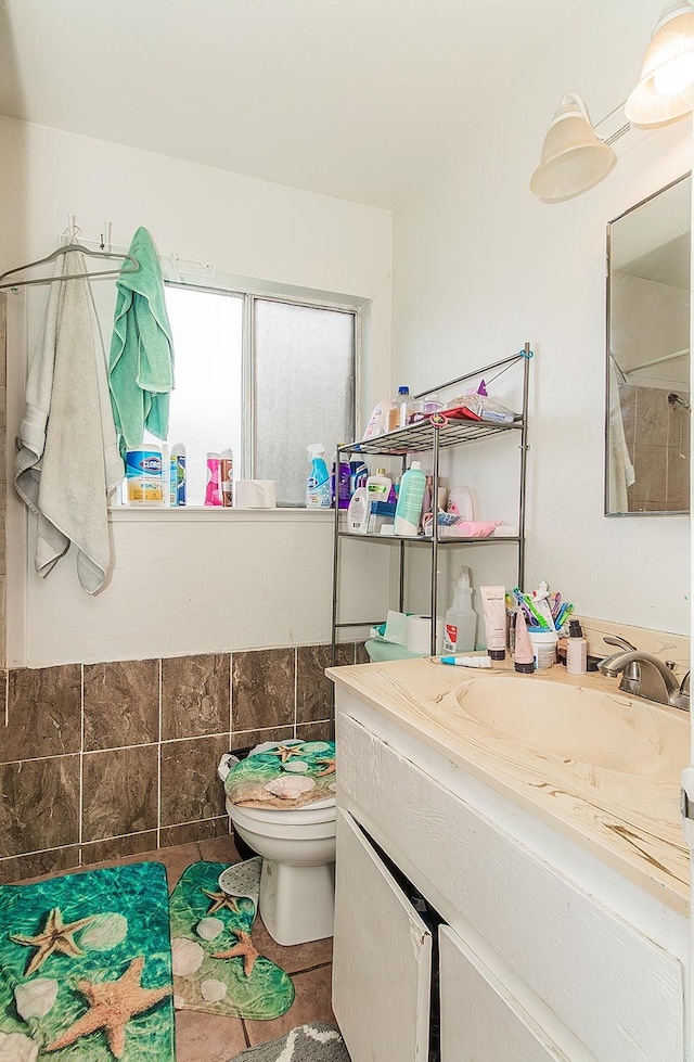 full bathroom with vanity, a wainscoted wall, tile walls, toilet, and tile patterned floors