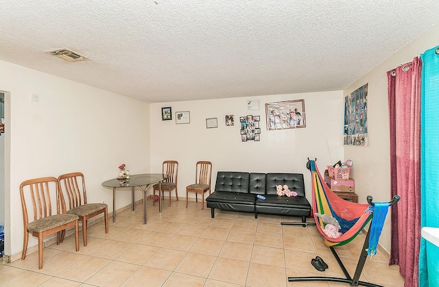 sitting room with light tile patterned flooring, visible vents, and a textured ceiling