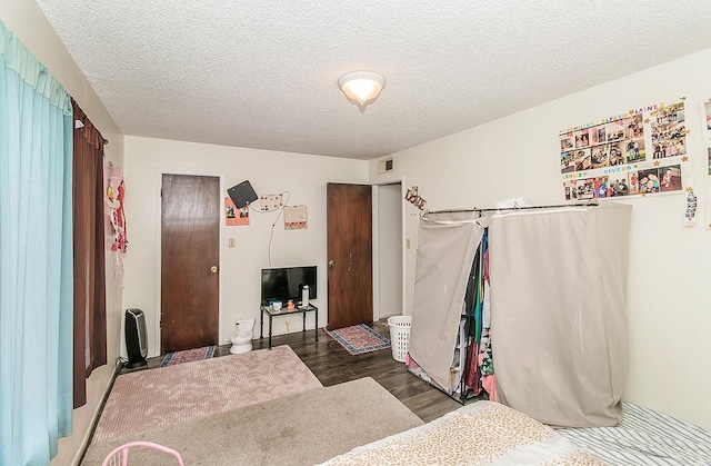 bedroom with visible vents, a textured ceiling, and wood finished floors