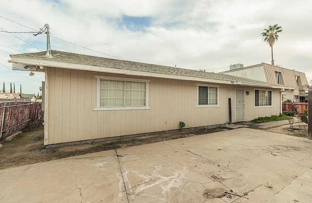 view of front of home featuring a patio, fence, and roof with shingles