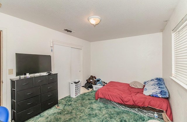 carpeted bedroom featuring visible vents, a textured ceiling, and a closet