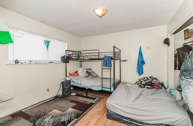 bedroom with a textured ceiling and wood finished floors