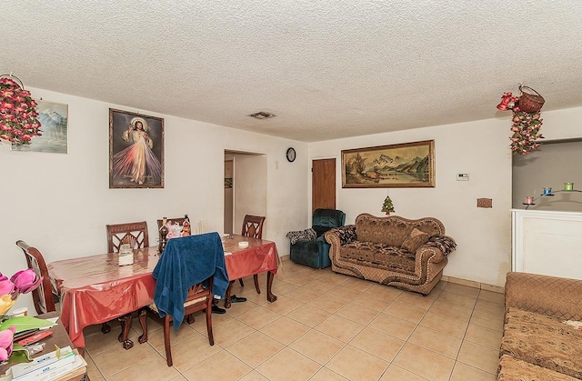 dining room featuring light tile patterned floors, visible vents, and a textured ceiling