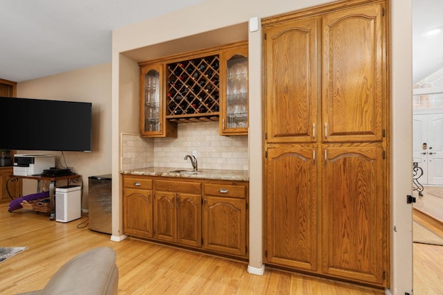 bar with wet bar, fridge, light wood-type flooring, and backsplash