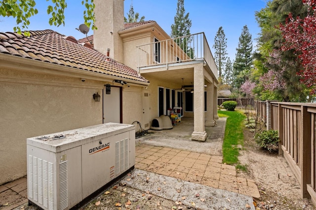 rear view of house with a balcony, a ceiling fan, a fenced backyard, a tile roof, and a patio area