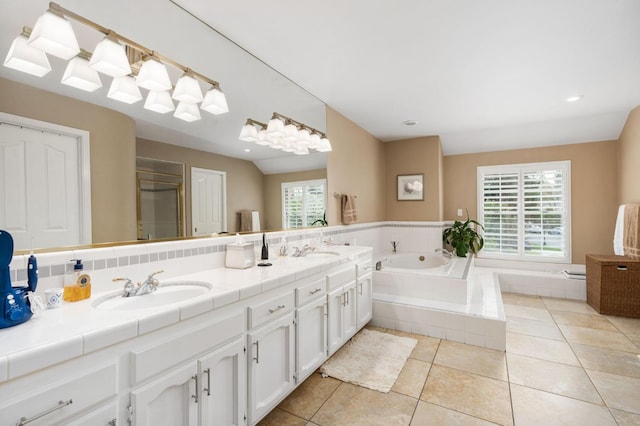 full bathroom with a garden tub, double vanity, tile patterned floors, and a sink