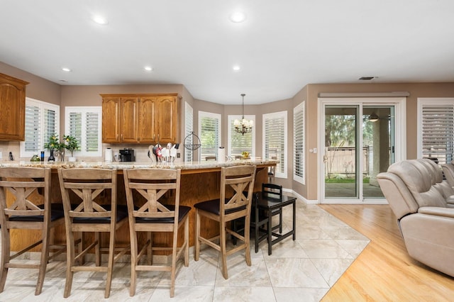 kitchen featuring light stone counters, recessed lighting, a breakfast bar area, and a healthy amount of sunlight