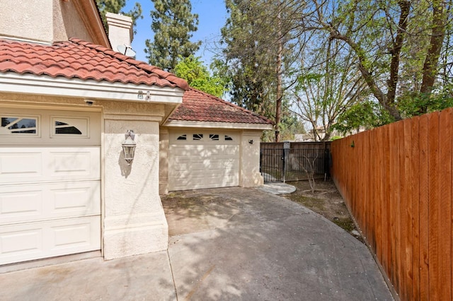 garage with concrete driveway, a gate, and fence