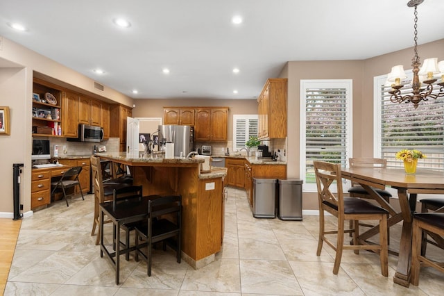 kitchen with backsplash, appliances with stainless steel finishes, a center island, and brown cabinets