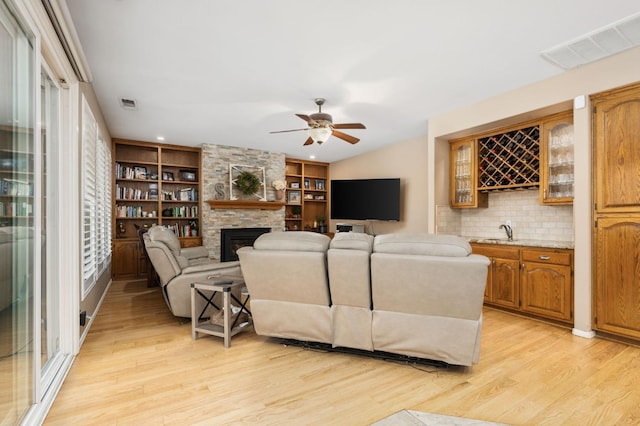 living area featuring indoor wet bar, visible vents, a fireplace, and light wood-style floors