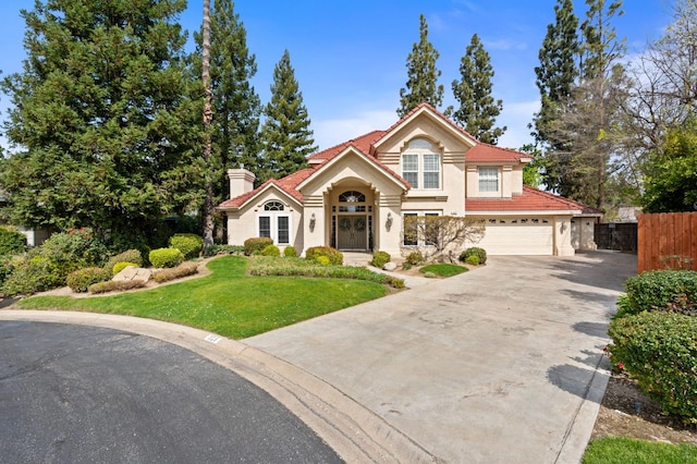 mediterranean / spanish-style house featuring a front yard, fence, a chimney, concrete driveway, and a tiled roof