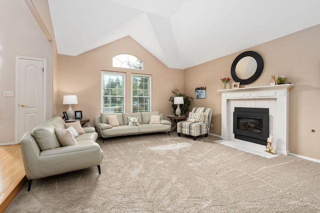 carpeted living room with a tiled fireplace, baseboards, and high vaulted ceiling