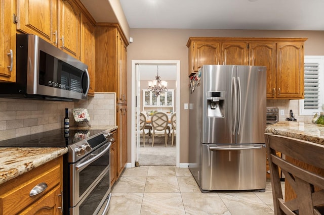 kitchen featuring brown cabinetry, backsplash, stainless steel appliances, and light stone counters