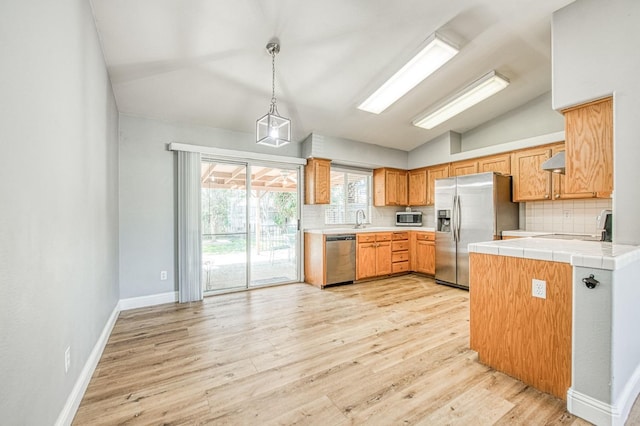 kitchen featuring vaulted ceiling, backsplash, stainless steel appliances, and a sink