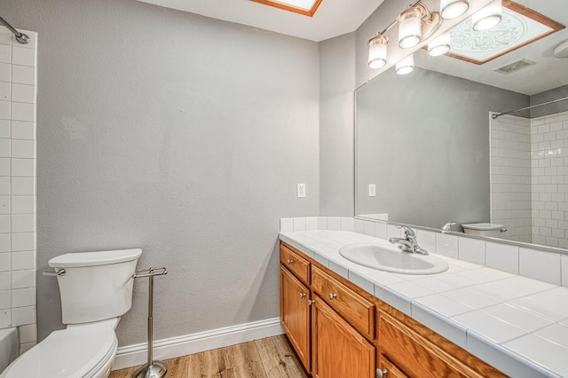 bathroom with visible vents, toilet, wood finished floors, a skylight, and baseboards