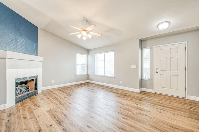 entryway featuring baseboards, vaulted ceiling, a fireplace, wood finished floors, and a ceiling fan