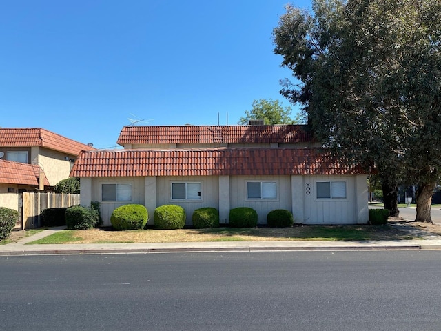 exterior space featuring a tiled roof and fence