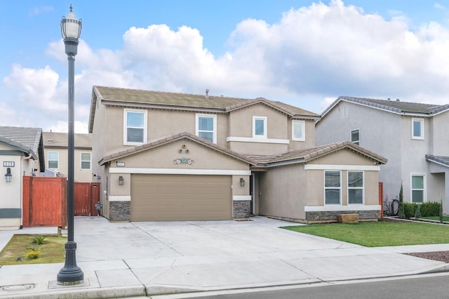 view of front of home featuring fence, stone siding, driveway, and stucco siding