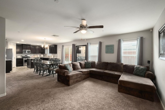 living room with visible vents, light carpet, baseboards, and ceiling fan with notable chandelier