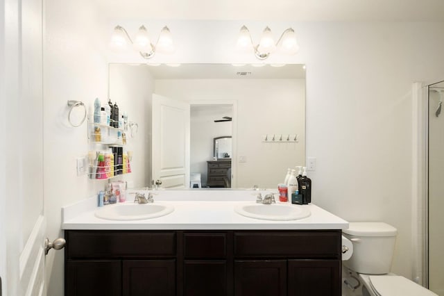 bathroom featuring double vanity, toilet, visible vents, and a sink