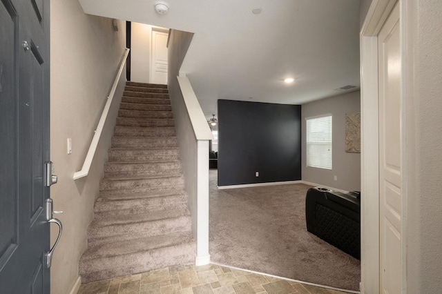 stairway with visible vents, baseboards, carpet flooring, and stone finish flooring