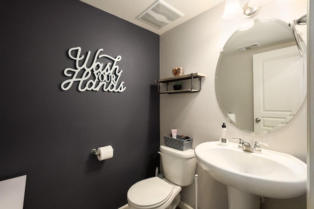 bathroom featuring toilet, visible vents, and a sink