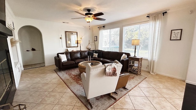 living room with light tile patterned floors, baseboards, visible vents, arched walkways, and ceiling fan