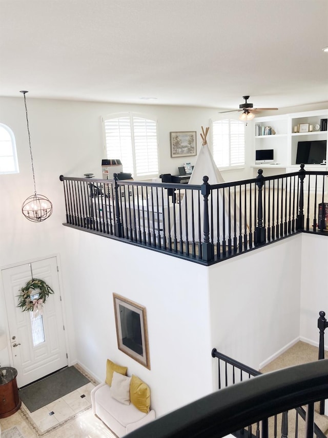 staircase with ceiling fan with notable chandelier and baseboards