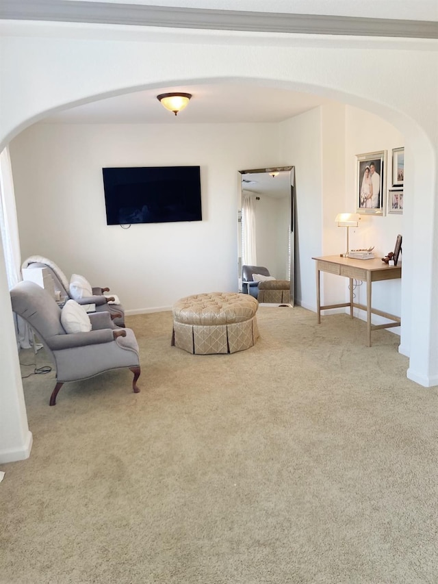 carpeted living room with baseboards and arched walkways