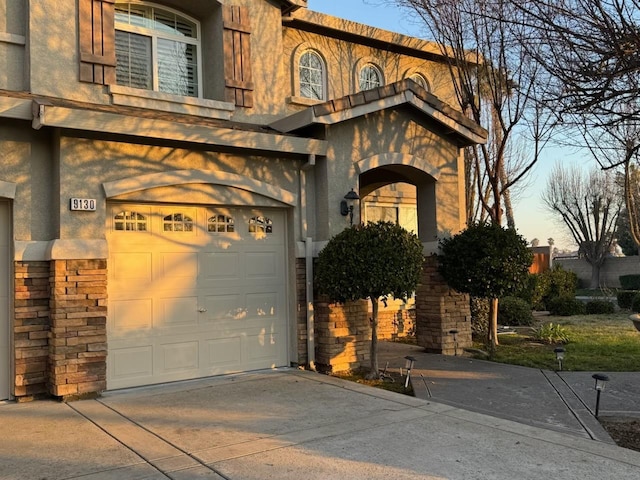 view of front of home featuring stone siding, stucco siding, driveway, and a garage