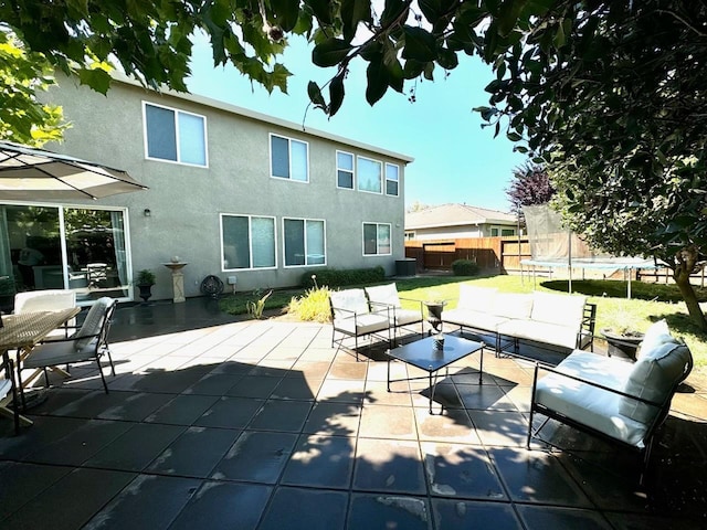 view of patio with outdoor lounge area, a trampoline, and fence