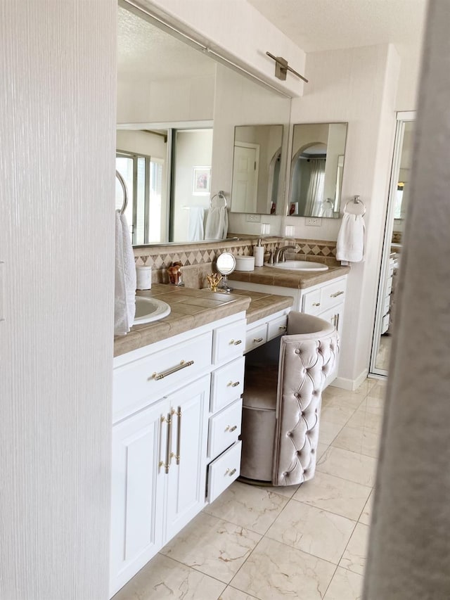 bathroom with decorative backsplash, double vanity, marble finish floor, and a sink