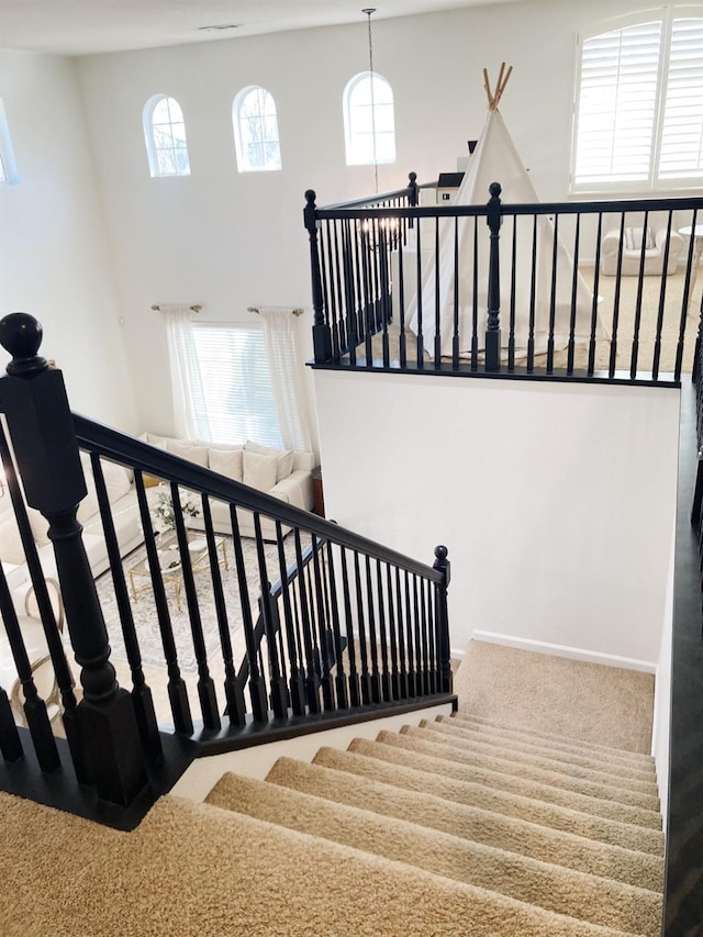 stairs featuring carpet flooring and a towering ceiling