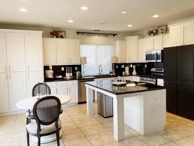 kitchen featuring stainless steel appliances, dark countertops, white cabinets, and a center island