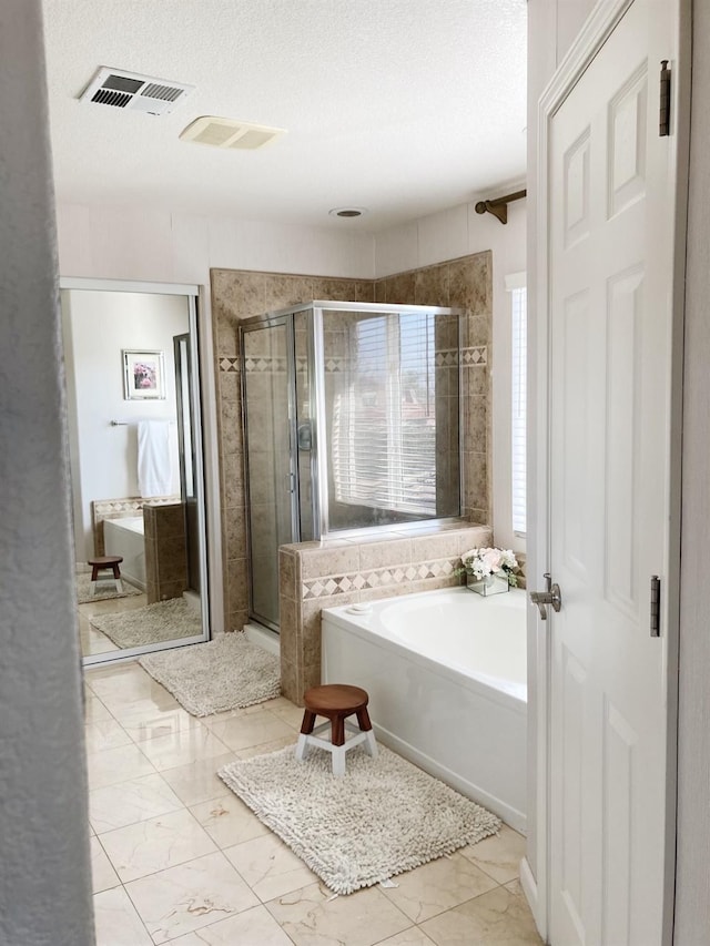 full bathroom featuring visible vents, a stall shower, a textured ceiling, a bath, and marble finish floor